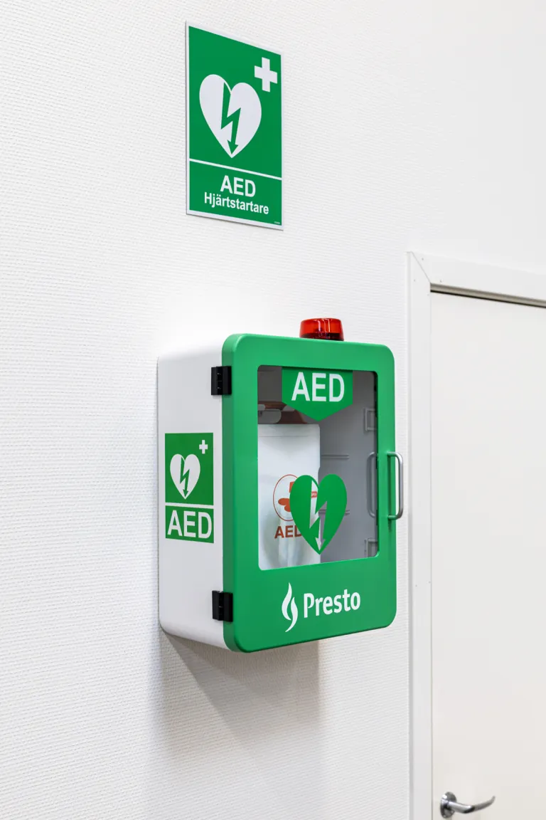 Grønt indendørs hjertestarterskab med Mediana A16 og AED-skilt